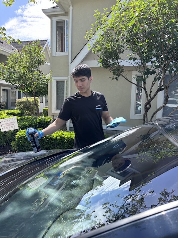Soheil, owner of Sparkwave Detailing, cleaning a windshield on-site